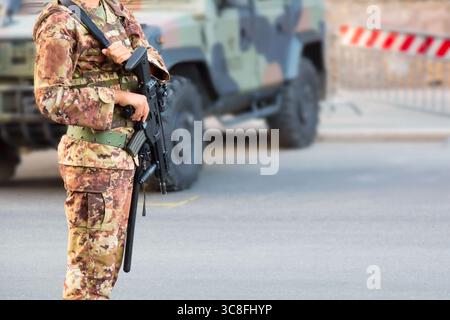Soldato con un fucile in uniforme italiana vicino a SUV militare blindato Foto Stock