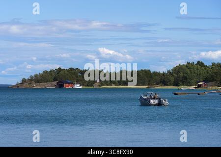 Parainen, Finlandia. 20 giugno 2025 - Vista dell'arcipelago finlandese con barca sull'acqua e tradizionali case in legno in estate Foto Stock