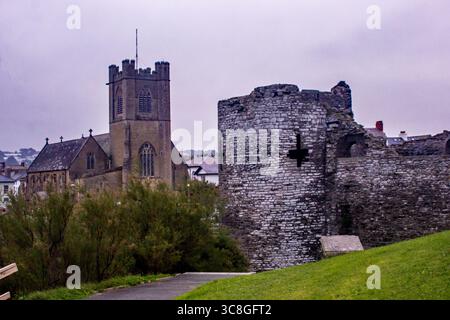 Resti di una torre del castello medievale di Aberystwyth con la chiesa di San Michele sullo sfondo in una mattina fredda e nebbiosa. Foto Stock