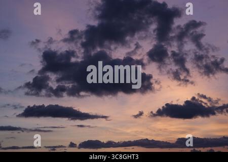 L'affascinante tramonto che illumina il cielo, con nuvole scure che ruotano sopra, creando un'atmosfera drammatica e lunare piena di colori Foto Stock
