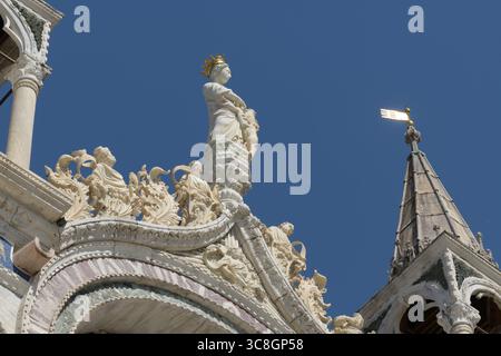 Dettaglio della decorazione ad arco in marmo con intarsi in porfido e santi sulla facciata della Basilica di San Marco, Venezia, Italia. Foto Stock