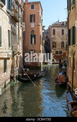 Stretto canale veneziano con gondole ed edifici rinascimentali a Venezia (Venezia), Italia, che mostra l'architettura tradizionale e la vita quotidiana dei canali. Foto Stock
