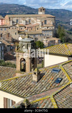 Vista dei tetti di Perugia, con una storica torre della chiesa e lussureggianti colline sullo sfondo. L'architettura presenta classici tetti piastrellati Foto Stock