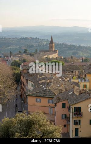 Veduta della Chiesa di Santa Giuliana a Perugia, circondata da colline umbre e cipressi sotto la morbida atmosfera serale Foto Stock