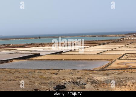 Salinas de Janubio, traditional salt flats on Lanzarote, Canary Islands, with geometric patterns and volcanic landscape in the background. Stock Photo
