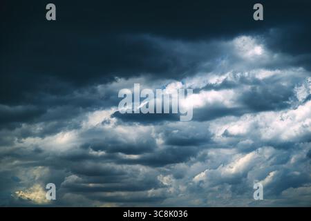 Nuvole di tempesta scure e drammatiche che si formano nel cielo, segnalano un temporale in avvicinamento. Ambientazione meteorologica in condizioni atmosferiche mostruose con una forte copertura delle nuvole e un'atmosfera suggestiva Foto Stock