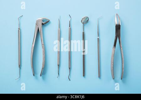 La salute dentale e il concetto di teetcare. Vista dall'alto degli strumenti dentali impostati su sfondo blu nella clinica dentistica: Specchio dentale, esploratori, pinzette Foto Stock