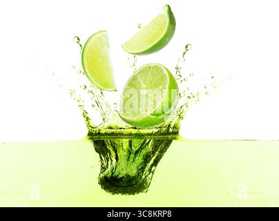 Limes freschi che cadono in una bevanda da spruzzo su sfondo bianco Foto Stock