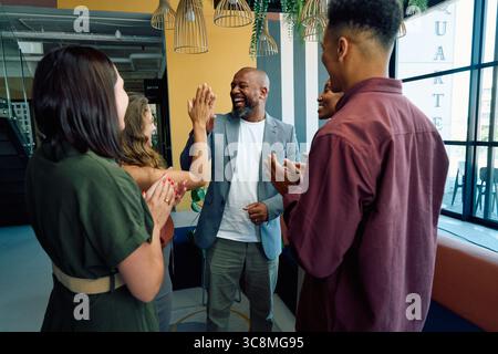 Diversi colleghi che celebrano un uomo d'affari di successo con cinque in carica durante il giorno Foto Stock