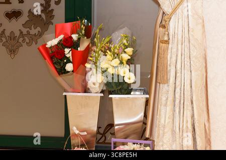 Una collezione di composizioni floreali in vasi decorativi. La scena include vari fiori nei colori rosa, bianco e viola Foto Stock