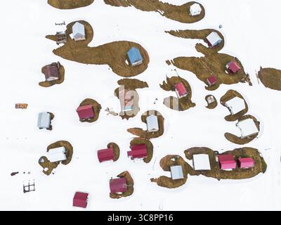 Vista aerea di edifici dai tetti colorati che sbirciano attraverso la neve bianca, creando un vibrante contrasto nel paesaggio, goderdzi, Adjara, Georgia. Foto Stock