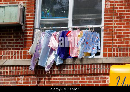 Asciugatura degli indumenti su una linea di lavaggio della clothesline fuori dalla finestra di un condominio. Foto Stock