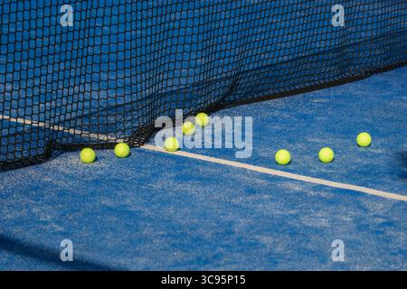 Palle di padel su una superficie sintetica blu, palle da tennis all'aperto accanto alla rete, concetto di gioco Foto Stock