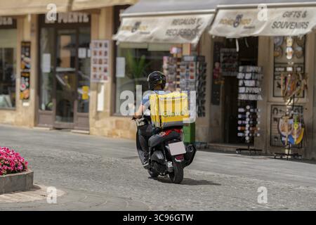 Ronda, malaga, spagna 20 giugno 2022 Vista posteriore di un giovane corriere glovo su una moto in città Foto Stock