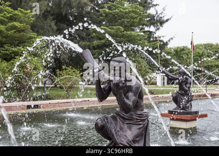 Accra, Ghana - 27 maggio 2017: Veduta di figure scolpite tra le acque delle fontane a cascata, una sinfonia di bronzo sullo sfondo verdeggiante. Foto Stock