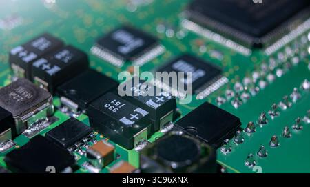 Vista dettagliata di una scheda a circuito stampato elettronica che mostra più componenti, resistenze e circuiti integrati tipici dei dispositivi moderni. Foto Stock