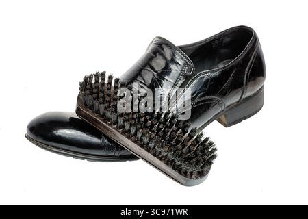 Scarpe per la pulizia o concetto di cura delle scarpe, spazzola in legno su scarpe nere pulite isolate su bianco. Messa a fuoco selettiva Foto Stock