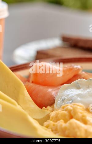 Un delizioso piatto da colazione con uova strapazzate, salmone fresco e salsa cremosa, perfetto per un'esperienza gourmet Foto Stock