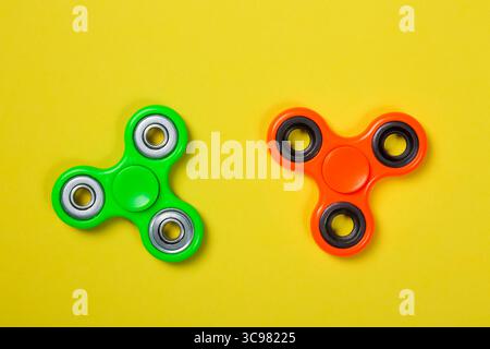 Le rotelle arancioni e verdi chiudono i giocattoli che alleviano lo stress su sfondo giallo Foto Stock