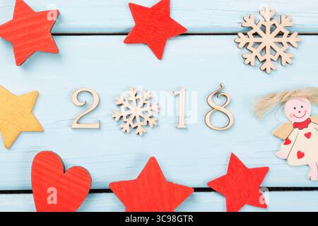2018 felice anno nuovo. Decorazioni natalizie con stelle rosse, gialle, angelo, fiocco di neve e cuore su sfondo in legno azzurro. 2018 legno decorativo in legno Foto Stock