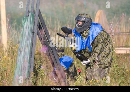 Paintball giocatori sportivi in uniforme protettiva e maschera giocare e sparare con la pistola all'aperto Foto Stock