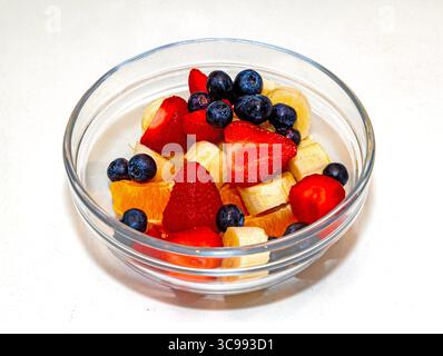 Macedonia di frutta fresca biologica tagliata all'interno di un recipiente di vetro su sfondo bianco Foto Stock