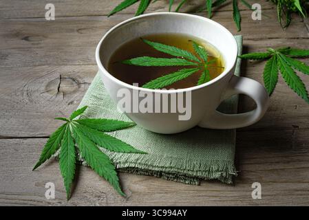 Tè alle erbe di canapa e foglie di canapa verde su un tavolo di legno. Bevanda calmante naturale per un sonno sano. Foto Stock