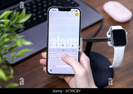 Poznan, Polonia - 29 luglio 2025: Digitazione manuale su uno smartphone con ios 26 e Liquid Glass, che mette in evidenza comunicazioni digitali efficienti e personali Foto Stock