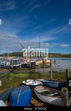 Piccole barche in una giornata di sole. Vista della banchina con la bassa marea sul fiume Deben nella storica città di Woodbridge nel Suffolk, Regno Unito. Foto Stock
