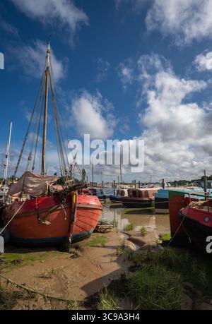 Barche sedute sul fango sotto un cielo tempestoso. Vista della banchina con la bassa marea sul fiume Deben nella storica città di Woodbridge, Suffolk, Regno Unito. Foto Stock