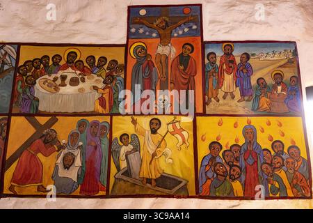 Kalacha, Kenya - 12 maggio 2022: Veduta di vivaci murales raffiguranti scene bibliche, che gettano un'ombra narrativa sul muro bianco testurizzato della chiesa di Kalacha. Foto Stock