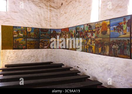 Kalacha, Kenya - 12 maggio 2022: Veduta di una serie di murales dai colori vivaci che adornano le pareti testurizzate sopra pali di legno scuro, inondati di luce soffusa. Foto Stock