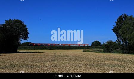 Passando il grano maturo sotto i cieli azzurri del Lancashire Occidentale a Northern è un servizio che collega Southport a Manchester Oxford Road Foto Stock