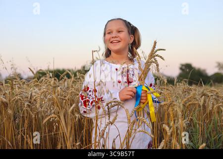 Felice ragazza Ucraina in vyshyvanka tiene un panello d'oro di grano, con nastri gialli e blu. simboleggiando il ricco raccolto di grano della nazione. Independe Foto Stock