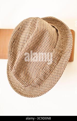 Cappello pied de poule appeso su una cremagliera di legno. Stile classico. Foto Stock