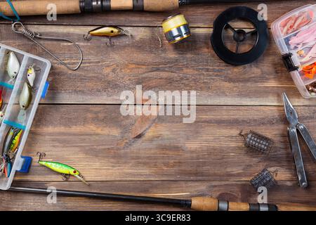 Incorniciare gli attrezzi da pesca e le esche da pesca in scatole su fondo in legno. Foto Stock