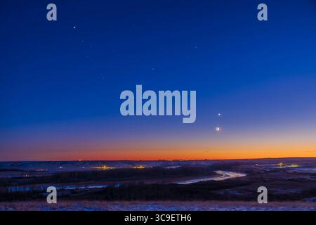 6 dicembre 2021, Alberta, Canada: Questa è la formazione di pianeti attraverso il cielo sudoccidentale il 6 dicembre 2021, composta da (da L a R): Giove, Saturno e Venere, con la luna crescente di 2,5 giorni in congiunzione sotto Venere. La Luna aveva eclissato il Sole due giorni prima, il 4 dicembre, quando era sull'eclittica. Due giorni dopo era sotto la linea eclittica. Giove e Saturno sono a Capricorno, con le sue stelle tutte visibili qui al crepuscolo serale. I tre pianeti sono ben equidistanti. Tale array rende visibile la linea eclittica. La posizione si affaccia sul Bow R. Foto Stock