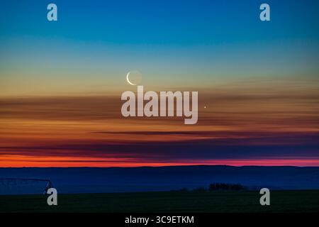 26 giugno 2022, Alberta, Canada: La congiunzione della luna crescente calante con Venere mentre si stavano alzando in basso nel cielo dell'alba nord-est il 26 giugno 2022, presa da casa nel sud dell'Alberta, latitudine 51Â N. Earthshine è visibile sul lato oscuro della Luna. Il cielo mostra la meravigliosa transizione di colori dall'arancione all'orizzonte attraverso lo spettro al blu in alto...si tratta di un'esposizione di 1 secondo con l'obiettivo RF70-200mm a 200mm e f/4 sulla Canon R5 a ISO 400. (Immagine di credito: © Alan Dyer/VW Pics via ZUMA Press Wire) Foto Stock