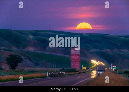 11 agosto 2022, Alberta, Canada: The Full Moon Rise of August 11, 2022 over the Old grain elevator on Highway 10 at Dorothy, Alberta, nelle Badlands della valle del Red Deer River. Questa è stata soprannominata "superluna" e "Sturgeon Moon" dai media popolari. E' successo che si è alzato in una posizione che l'ha collocata proprio lungo l'autostrada rivolta a sud-est nella valle. Ho usato l'app Photographer's Ephemeris per localizzare lo spot per scattare la foto! Si tratta di un'esposizione singola di 1,6 secondi con Canon R5 a ISO 800, sul rifrattore apo William Optics 66mm f/7 per una lunghezza focale di 460mm. Tuttavia, Foto Stock