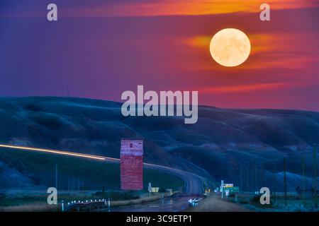 11 agosto 2022, Alberta, Canada: The Full Moon Rise of August 11, 2022 over the Old grain elevator on Highway 10 at Dorothy, Alberta, nelle Badlands della valle del Red Deer River. Questa è stata soprannominata "superluna" e "Sturgeon Moon" dai media popolari. E' successo che si è alzato in una posizione che l'ha collocata proprio lungo l'autostrada rivolta a sud-est nella valle. Ho usato l'effemeride del fotografo per localizzare il punto per scattare la foto! Si tratta di una miscela di due esposizioni: Esposizione di 6 secondi per il suolo e 1/4 secondo per la Luna, distanti momenti ed entrambe con la Canon R5 a ISO 800 Foto Stock