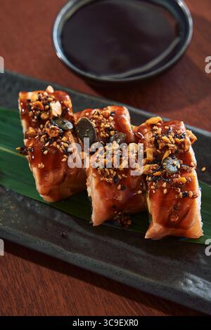 Sushi Rolls preparati con gusto e conditi con condimento salato e salsa dolce su un piatto elegante, perfetti per un'esperienza gastronomica gourmet Foto Stock