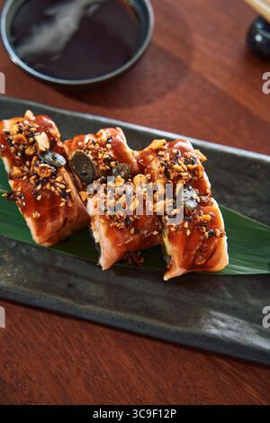 Sushi Rolls preparati in modo delizioso con salsa salata, noci e semi serviti su un piatto elegante con un lato di salsa di soia Foto Stock
