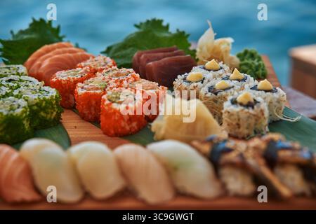 Un vivace assortimento di sushi con ingredienti freschi e vari stili come maki e nigiri, splendidamente disposti su un piatto di legno del wat Foto Stock