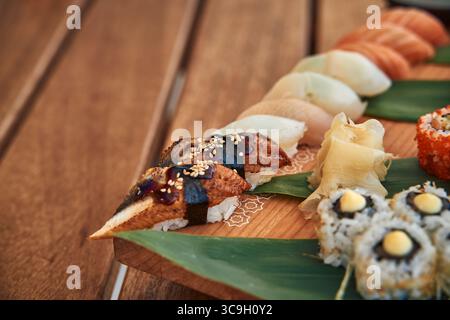 Una selezione splendidamente organizzata di varietà di sushi su un piatto di legno, che mostra pesci colorati, riso e ingredienti freschi Foto Stock