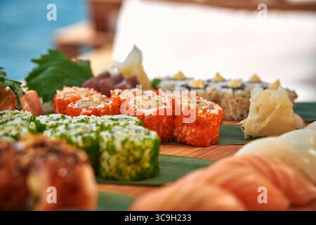 Un delizioso piatto di sushi ben organizzato con vari tipi di panini, ingredienti freschi e decorazioni, perfetto per qualsiasi amante del sushi Foto Stock