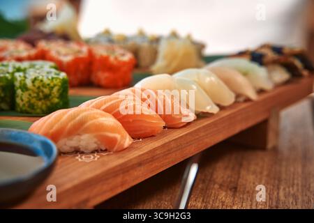 Un piatto di sushi fresco splendidamente organizzato con vari tipi di pesce, rotoli colorati e accompagnamenti per una delizia culinaria Foto Stock