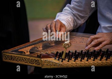Primo piano delle mani di un musicista che suona un tradizionale Kanun turco ornato, uno strumento a corde mediorientale che utilizza picchetti metallici a Istanbul, Turchia Foto Stock