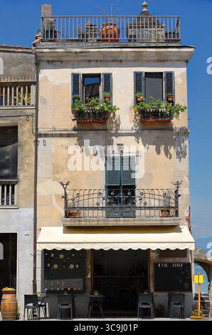 165 edificio vecchio a tre piani in Piazza Mazzini con un negozio di cibo e bevande, finestre fiorite, terrazza sul tetto. Castiglione del Lago-Umbria-Italia Foto Stock