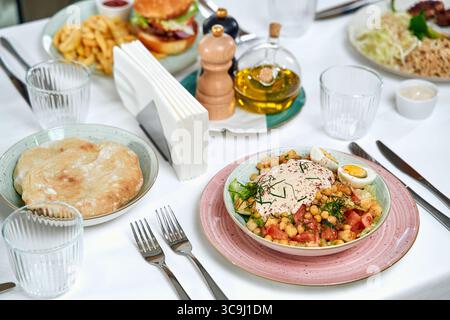 Una deliziosa gamma di piatti su un tavolo da pranzo con ingredienti freschi, decorazioni e accompagnamenti tradizionali in un ambiente culinario Foto Stock