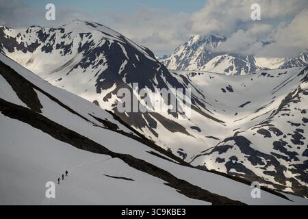 Gli escursionisti camminano attraverso il terreno innevato e montuoso del Kenai Fjords National Park. Il parco vanta ghiacciai, fiordi e un'abbondante fauna selvatica. Foto Stock
